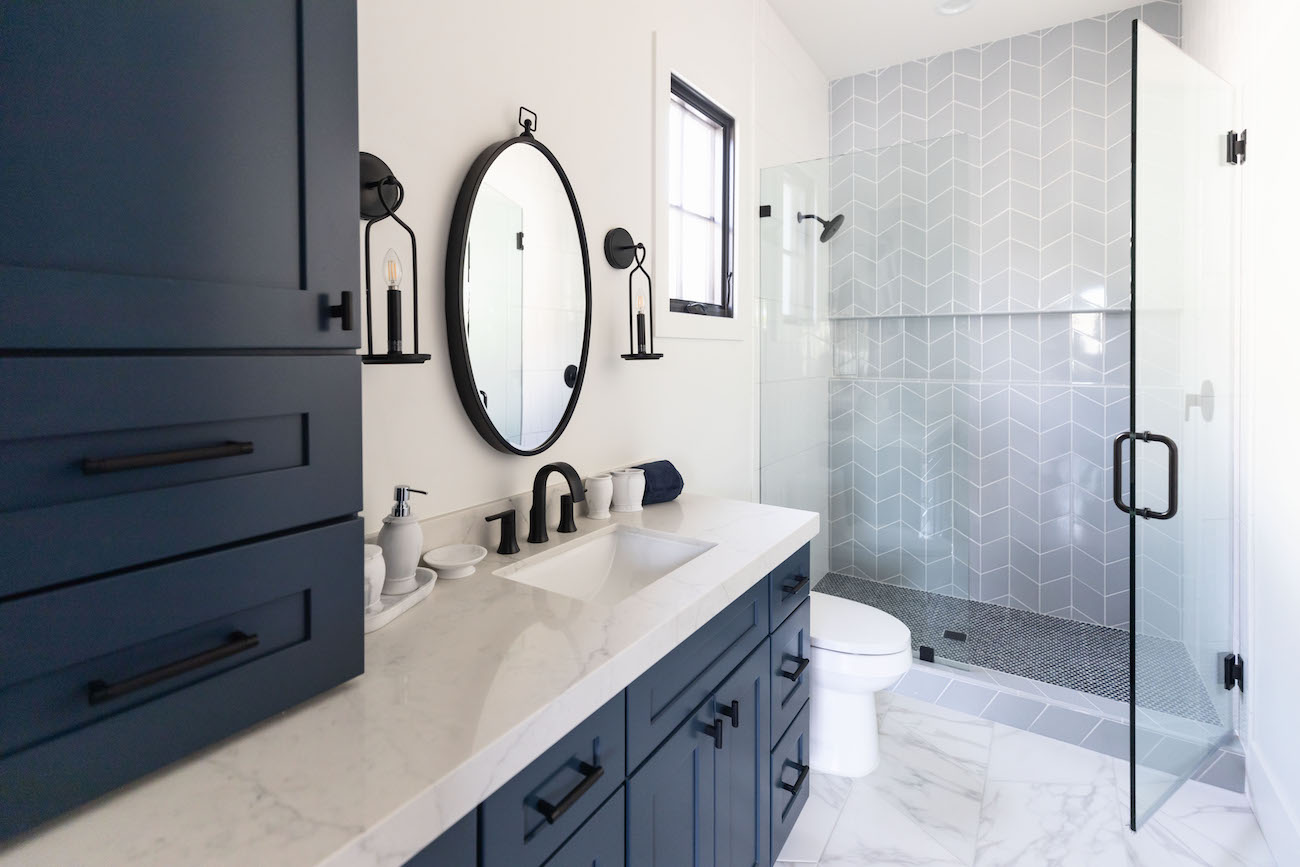 bathroom-design-navy-blue-cabinetry-round-mirror