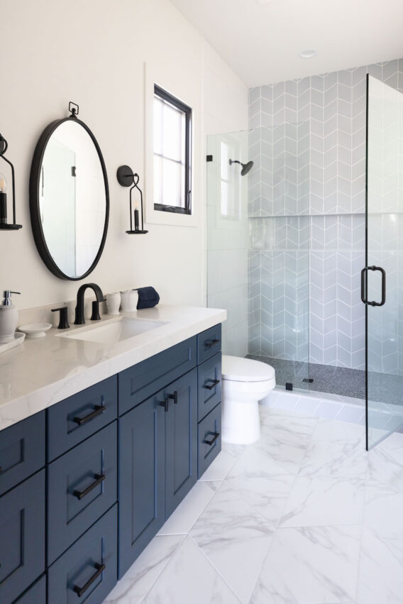 bathroom-design-round-mirror-navy-cabinets-black-hardware